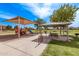 Community playground with play structures, shaded picnic area, and lush green surroundings at 45574 W Tulip Ln, Maricopa, AZ 85139