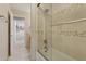 Neutral-toned bathroom with tiled shower-tub combination plus clear glass doors and view into laundry room at 4718 E Woburn Ln, Cave Creek, AZ 85331