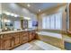 Bathroom featuring double sinks, granite countertops, soaking tub, and plantation shutters at 6519 E Cactus Rd, Scottsdale, AZ 85254