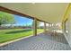 Covered patio with brick pavers and views of the lush green lawn and basketball court at 6519 E Cactus Rd, Scottsdale, AZ 85254