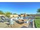 Inviting outdoor pool area with ample seating, lounge chairs and a brick firepit under a blue sky at 6519 E Cactus Rd, Scottsdale, AZ 85254