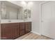 Bathroom with wood cabinets, double sinks, large mirror and tile floors at 7229 E Cattle Call St, San Tan Valley, AZ 85143