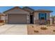 Charming home featuring a gray stucco exterior, blue shutters, desert landscaping and a large two car garage at 7229 E Cattle Call St, San Tan Valley, AZ 85143