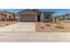 Charming home featuring a gray stucco exterior, blue shutters, desert landscaping and a large two car garage at 7229 E Cattle Call St, San Tan Valley, AZ 85143