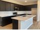 Modern kitchen featuring sleek black cabinetry, stainless steel appliances, a center island, and white subway tile backsplash at 7229 E Cattle Call St, San Tan Valley, AZ 85143