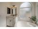 Bright bathroom featuring a vanity and a tub, complemented by an arched window at 7297 E Black Rock Rd, Scottsdale, AZ 85255