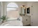 Bright bathroom features a large soaking tub, arched window, and a vanity with a framed mirror at 7297 E Black Rock Rd, Scottsdale, AZ 85255