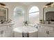 Elegant bathroom with dual vanities, a corner soaking tub, and arched windows at 7297 E Black Rock Rd, Scottsdale, AZ 85255
