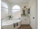 Serene bathroom features a soaking tub, vanity with modern fixtures, and arched window at 7297 E Black Rock Rd, Scottsdale, AZ 85255
