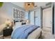 Stylish bedroom featuring a queen-sized bed with blue bedding, a modern light fixture, and a light-colored wall at 8251 E Petunia Ave, Mesa, AZ 85212