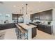 Stylish kitchen featuring a central island with seating and pendant lights, alongside dark cabinets and modern appliances at 8251 E Petunia Ave, Mesa, AZ 85212