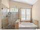 Spa-like bathroom with a glass-enclosed shower, soaking tub, and travertine tile at 93 S Sandstone St, Gilbert, AZ 85296