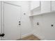 Bright laundry room with storage cabinets, a utility sink, and a doorway to the house at 1029 E Ian Dr, Phoenix, AZ 85042