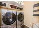 This laundry room includes Whirlpool washer and dryer and storage shelves at 10507 S 181St Ave, Goodyear, AZ 85338