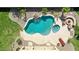 Aerial view of a pristine backyard pool with a rock waterfall, spa, and fire pit surrounded by lush, green landscaping at 11150 S Star Ct, Goodyear, AZ 85338