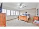 Bright main bedroom featuring neutral carpet, ceiling fan, and windows with shutters at 11150 S Star Ct, Goodyear, AZ 85338