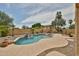 Backyard pool featuring a rock waterfall, spa, lush landscaping, and a comfortable lounge chair for relaxing by the water at 11150 S Star Ct, Goodyear, AZ 85338