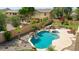 Inviting backyard featuring a pool, spa, waterfall feature, lush landscaping, and a cozy outdoor seating area with a fire pit at 11150 S Star Ct, Goodyear, AZ 85338