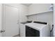 Bright laundry room features a white washer and dryer, along with overhead shelving at 13438 N 130Th Ln, El Mirage, AZ 85335