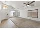 Bright living room featuring plush carpet, multiple windows, a ceiling fan, and natural light at 13438 N 130Th Ln, El Mirage, AZ 85335
