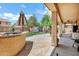 Covered patio featuring stone flooring, built in BBQ area, and view of the green backyard at 1565 E Prickly Pear Pl, Casa Grande, AZ 85122