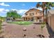 Spacious backyard with gravel, green lawn, mature trees, and a relaxing hot tub at 1565 E Prickly Pear Pl, Casa Grande, AZ 85122