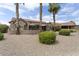 Desert backyard featuring a patio, decorative rock landscaping, and mature palm trees for shade and privacy at 16514 W Sandia Park Dr, Surprise, AZ 85374