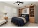 Inviting bedroom with dark blue bedding, tiled floors, built-in bookshelves, and natural light through shuttered windows at 16514 W Sandia Park Dr, Surprise, AZ 85374