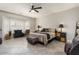 Spacious main bedroom featuring tiled floors, a ceiling fan, and ample natural light from a large bay window at 16514 W Sandia Park Dr, Surprise, AZ 85374