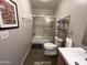 Neutral bathroom with shower-tub combo, dark tile floors, and shelving next to toilet at 1823 E Kirkland Ln # C, Tempe, AZ 85281