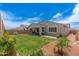 Green backyard with covered patio, outdoor furniture, colorful plants, and privacy fence at 19968 W Flower St, Buckeye, AZ 85396