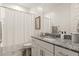 Bright bathroom featuring a granite countertop, shower with white curtain and framed botanical art at 19968 W Flower St, Buckeye, AZ 85396