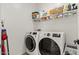 Modern laundry room featuring front-loading washer and dryer with overhead shelving for storage at 19968 W Flower St, Buckeye, AZ 85396