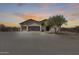 Inviting desert home featuring a stone facade, three-car garage, and mature landscaping against a scenic sunset backdrop at 30511 N 162Nd Way, Scottsdale, AZ 85262