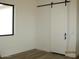 The bright bedroom has a barn door and wood-look tile flooring at 34449 N Elk Run Rd, San Tan Valley, AZ 85143