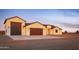Front elevation of the home featuring garage with an eye-catching stained wood-look door, surrounded by a desert landscape at 34449 N Elk Run Rd, San Tan Valley, AZ 85143