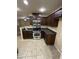 Compact kitchen with stainless steel appliances, tiled flooring, and dark wood cabinetry at 40246 W Hopper Dr, Maricopa, AZ 85138
