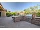 Outdoor kitchen area with a stone counter, built-in grill, and dining space perfect for entertaining guests in the backyard at 42023 N Bridlewood Way, Anthem, AZ 85086