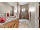 Well-lit bathroom with tile flooring, wood cabinetry, and a combined shower-tub with decorative tiling at 42023 N Bridlewood Way, Anthem, AZ 85086