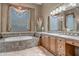 Elegant bathroom features a soaking tub with decorative tile surround and beautiful window treatments at 42023 N Bridlewood Way, Anthem, AZ 85086