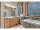 Bright bathroom featuring a soaking tub with decorative tile surround, beautiful window treatments and vanity at 42023 N Bridlewood Way, Anthem, AZ 85086
