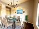 Bright dining room with modern chandelier, glass table, and seating for six guests at 42023 N Bridlewood Way, Anthem, AZ 85086