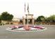 Landscaped entrance to community featuring a colorful flower bed and flag poles at the building entrance at 42023 N Bridlewood Way, Anthem, AZ 85086