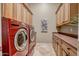 Well-organized laundry room featuring a striking red washer and dryer, ample cabinet space, and stylish tile flooring at 42023 N Bridlewood Way, Anthem, AZ 85086