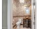 Elegant powder room featuring decorative mirror, stone vessel sink, and mosaic tile accents at 42023 N Bridlewood Way, Anthem, AZ 85086