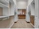 A large walk-in closet featuring ample white shelving and drawers, and wood paneling at 42023 N Bridlewood Way, Anthem, AZ 85086