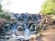 Community waterfall feature with multiple tiers of rocky streams at 42023 N Bridlewood Way, Anthem, AZ 85086