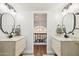 Dual vanity bathroom with wood cabinets, elegant mirrors, and a view to the staircase landing at 5556 E Sandra Ter, Scottsdale, AZ 85254