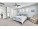 Bright main bedroom boasts a ceiling fan, three windows, neutral carpet, and ensuite bath access at 651 N Bay Dr, Gilbert, AZ 85233