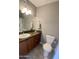 Well-lit bathroom with cherry cabinets, a sink, and a toilet at 7026 S 40Th Pl, Phoenix, AZ 85042